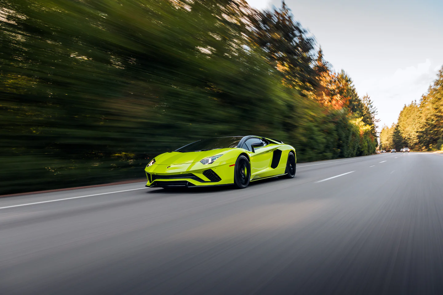 Lime green supercar at speed on a tree-lined road